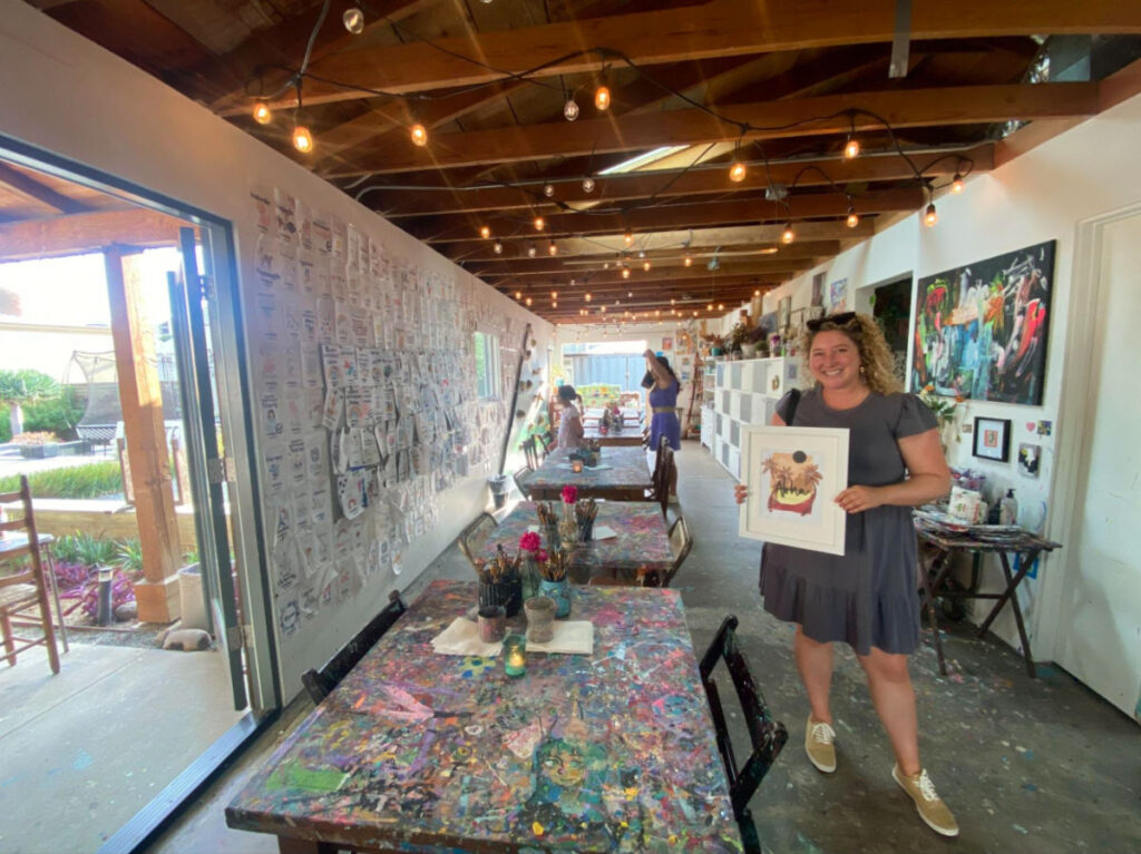 Author Jess holding a painting at Open Studio night