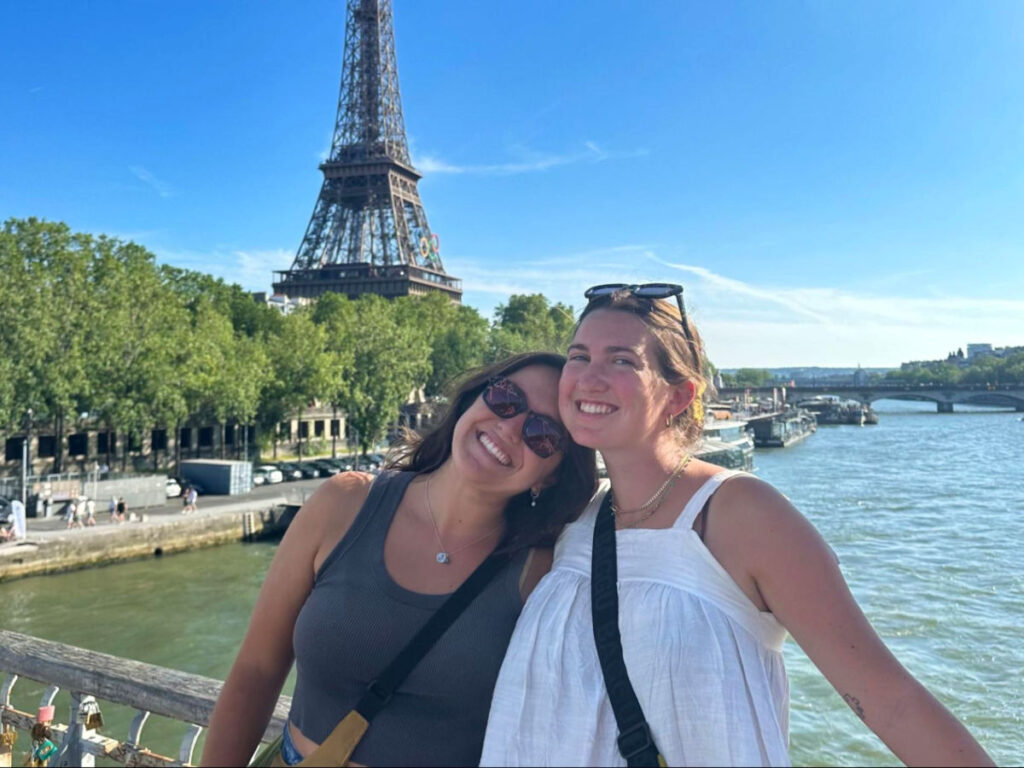 Author Laura and her partner posing for a photo near the river with a view of the Eiffel tower