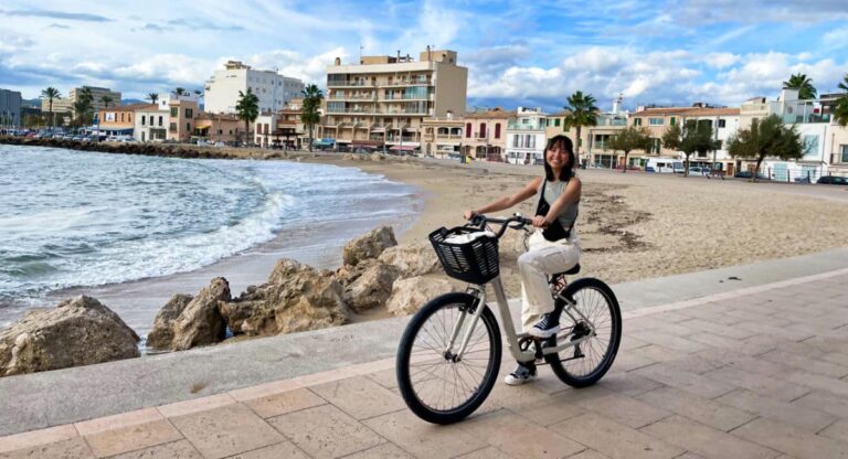 The author Lea Rose Allbaugh cycling around a local beach in Palma de Mallorca