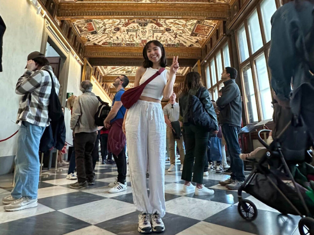 Author Lea Rose posing for a photo and showing the peace sign inside a museum