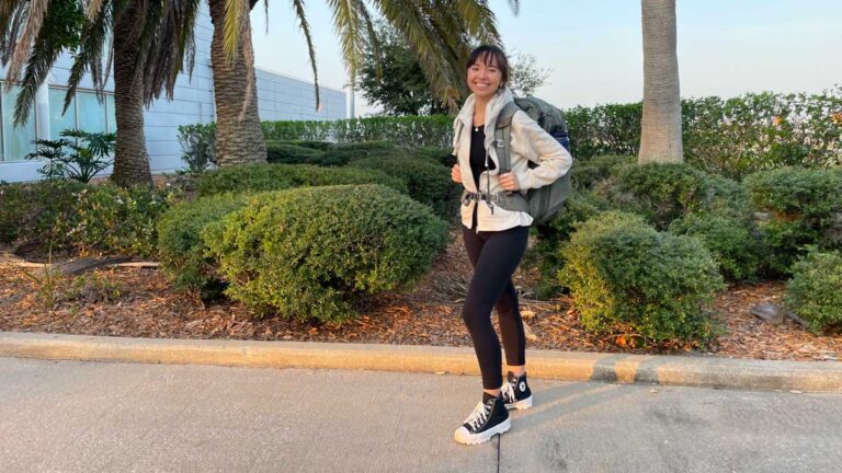 The author Lea Rose smiling for a photo while carrying Travel Backpack