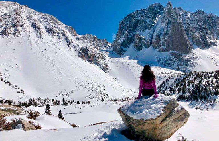 The author McKenna Mobley sitting on a boulder during her hike in Big Pine Lakes at winter surrounded by snow