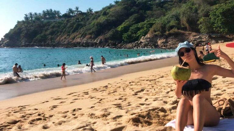 The author McKenna Mobley, holding a coconut water while posing on a beach in Oaxaca