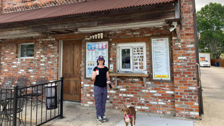 The author Meg with her dog, Milo in front of the Snowball Factory in New Iberia