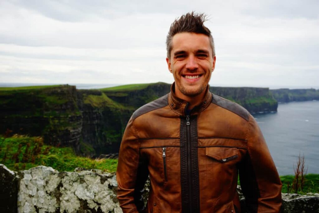 Author Nate smiling for a photo on a windy day at Cliffs of Moher