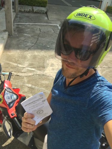 Author Nate wearing a helmet and holding his International Driving Permit