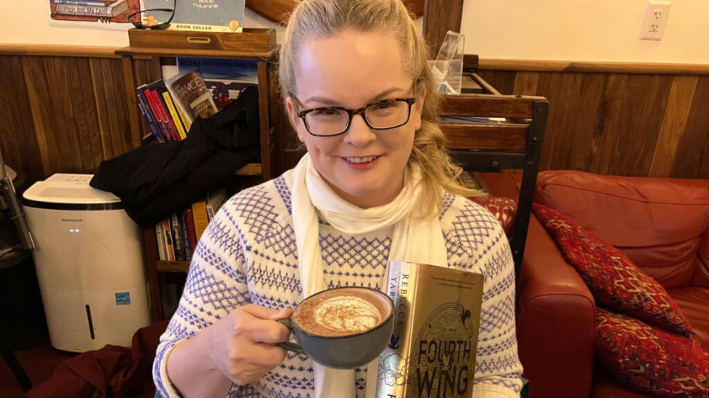 Author Rachel holding a cup of coffee and a book at Leopold’s in Madison