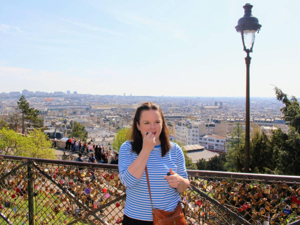 Author Rachel applying lipstick while at the love lock-covered railing near Sacré-Cœur Basilica