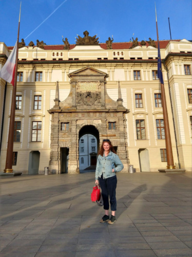 Author Ruthie holding a red bag outside a building in Prague