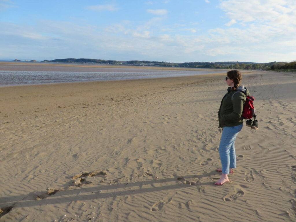 Author Ruthie standing on the sandy shore of Swansea beach
