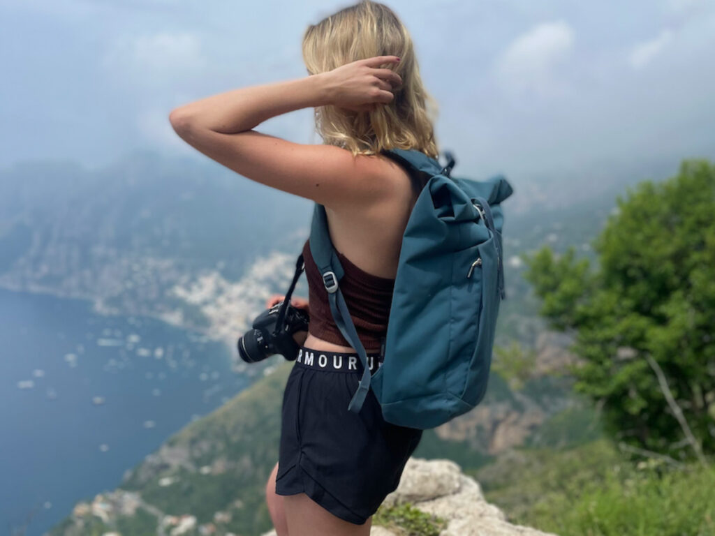 Author Sky, wearing a backpack and holding her camera, enjoying the view from a mountain top