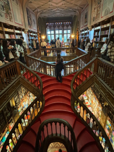 Author Sky standing at the winding staircases of Livraria Lello
