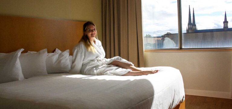 The author Taylor sitting on a bed in Holman Grand Hotel