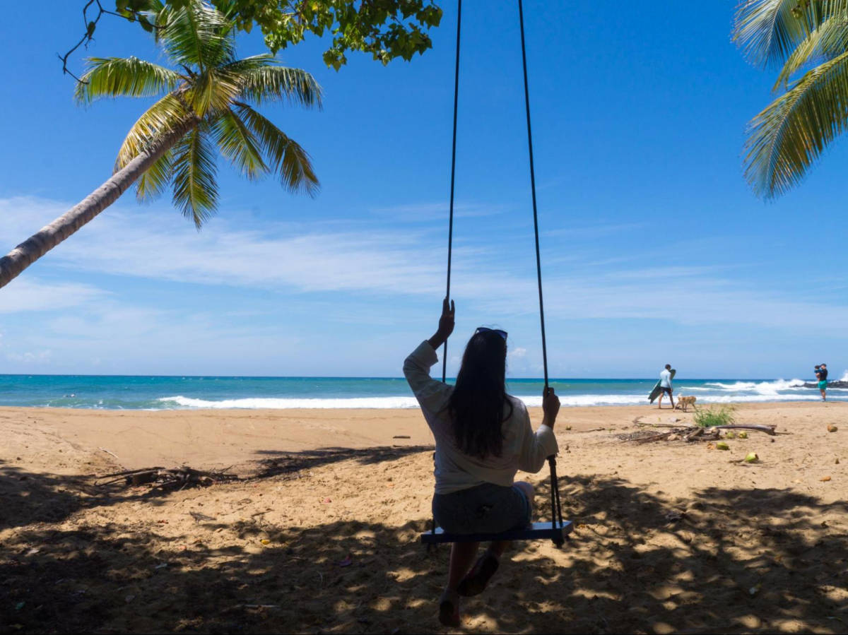 Author Vanessa looking at the sea while sitting on a swing at Domes Beach