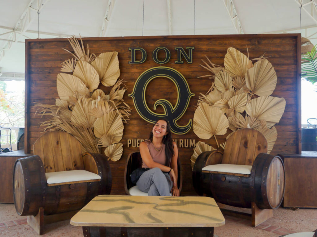 Author Vanessa sitting next to the Don Q sign