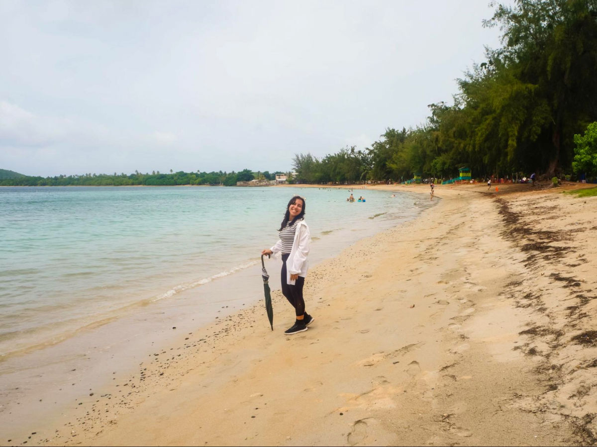 Author Vanessa standing at the Seven Seas Beach while holding an umbrella