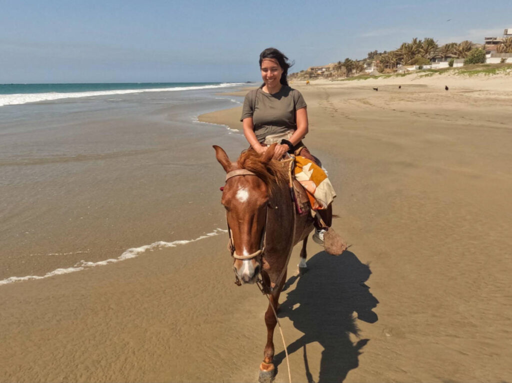 Author Vanessa riding a horse on the beach