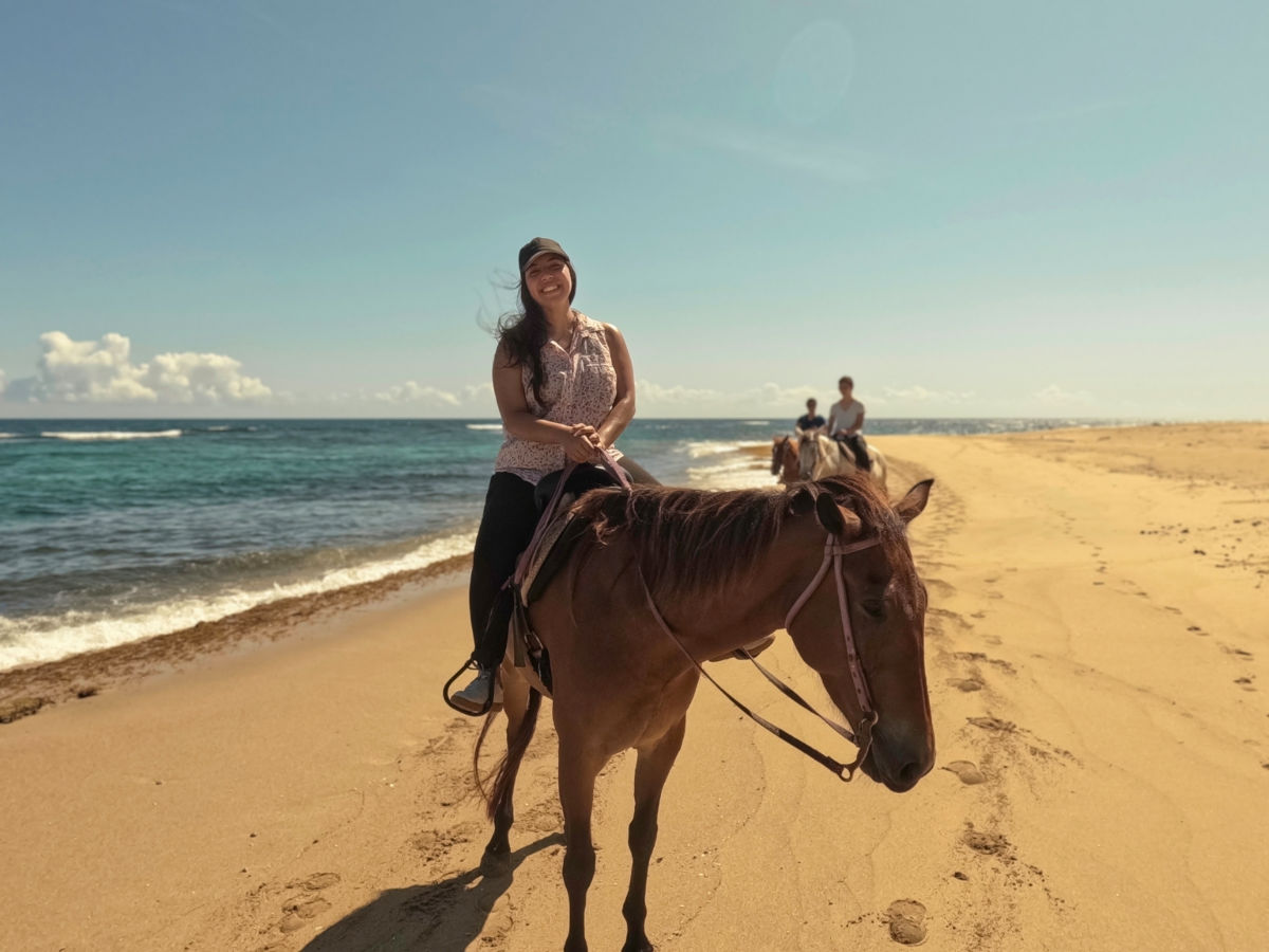 Author Vanessa riding a horse near the beach