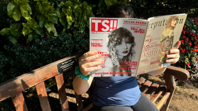 Author Elizabeth sitting on the Taylor Swift Bench while reading a TS magazine