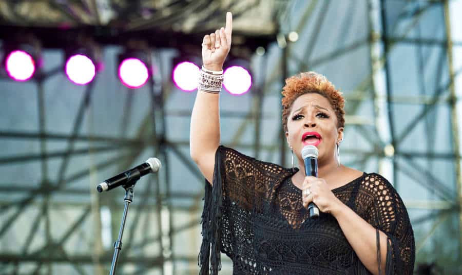Avery Sunshine holding a mic and performing on the stage