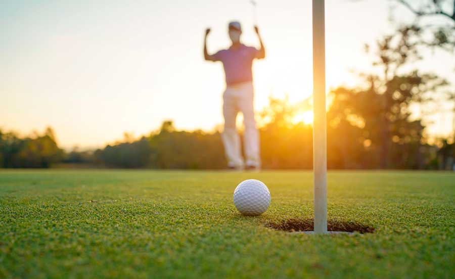 View of a golfer playing during sunset