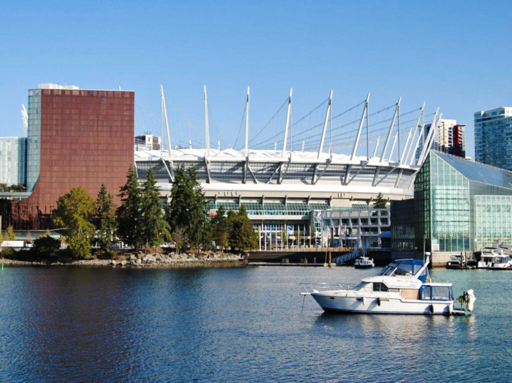 A boat sailing on the False Creek in front of the BC Place Stadium