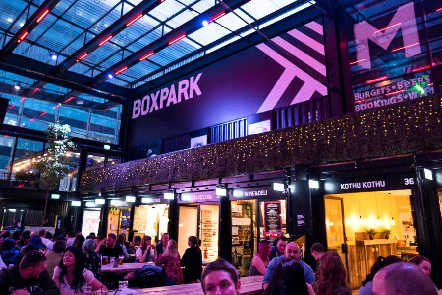 View inside the BOXPARK glowing with neon lights at night
