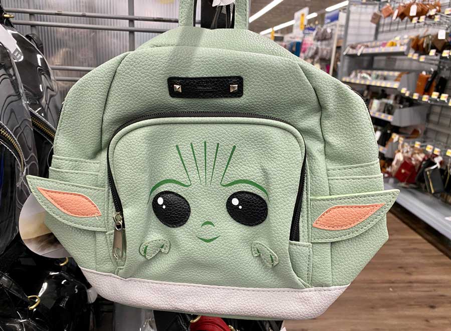 A baby Yoda backpack hanging on a store in Disneyland