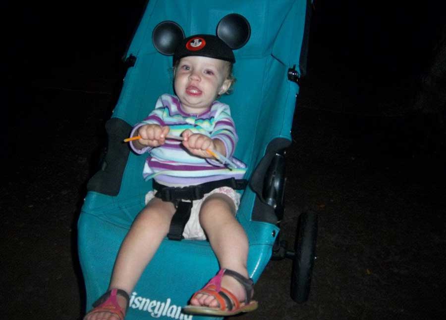 A baby with a Mickey Mouse ears on a stroller