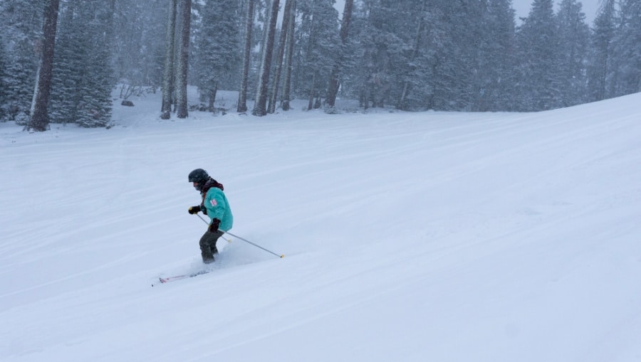 A man skiing at a snow covered slope with pine trees around Yosemite National Park.