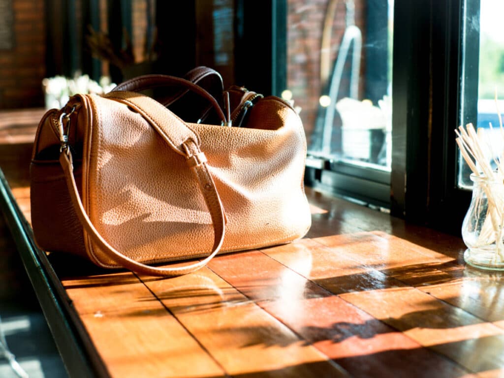 A brown bag on a wooden table near the bay window