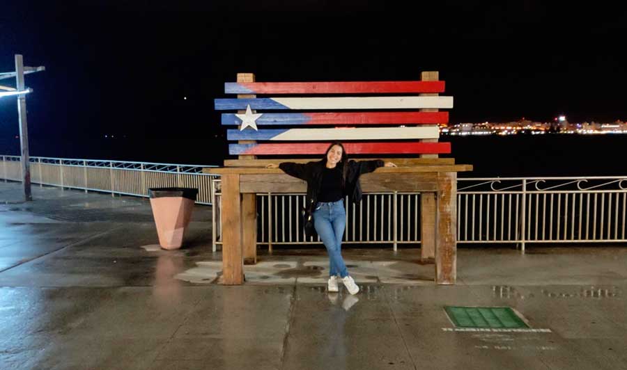 The author posing for a photo at night with the flag of Puerto Rico