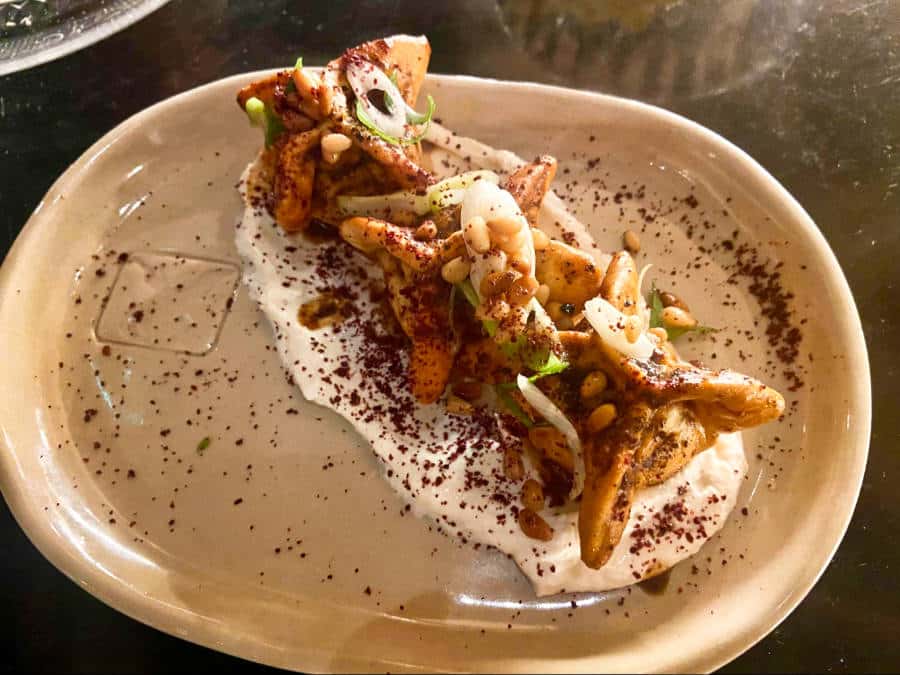 A serving of Lamb kebab dumplings with garlic yogurt and buttered pine nuts on an oval plate in Bala Baya.