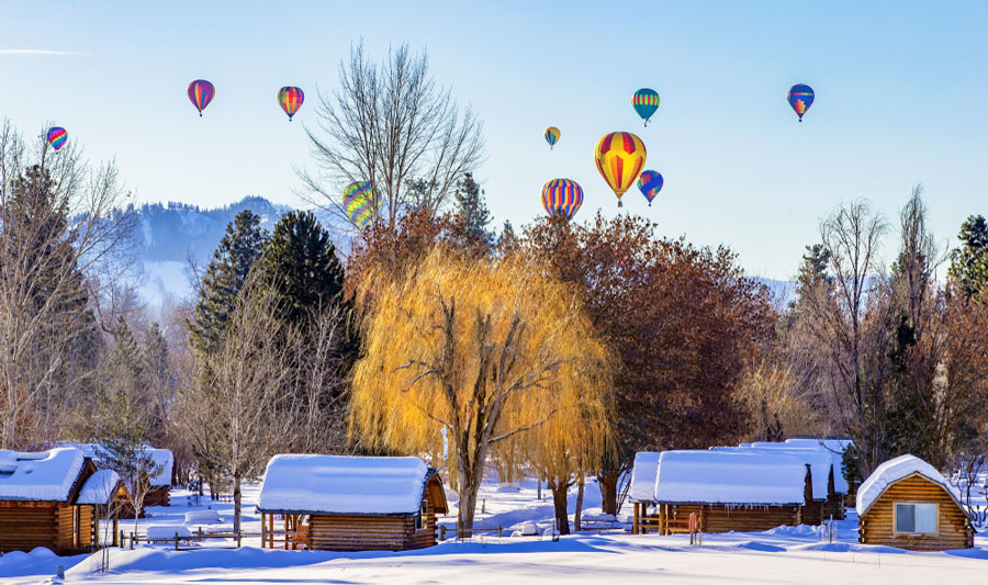 View of colorful hot air balloons above a snowy village 
