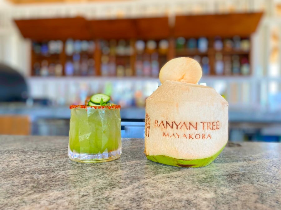 A glass of alcoholic drink and a coconut water on a table