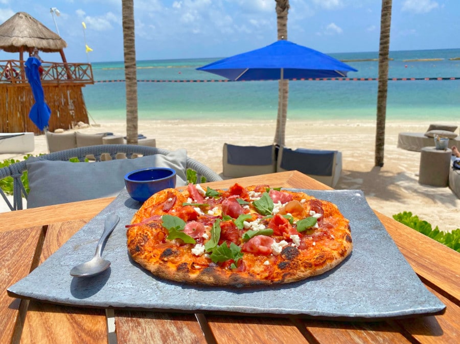 View of a pizza on a table an the beach from afar