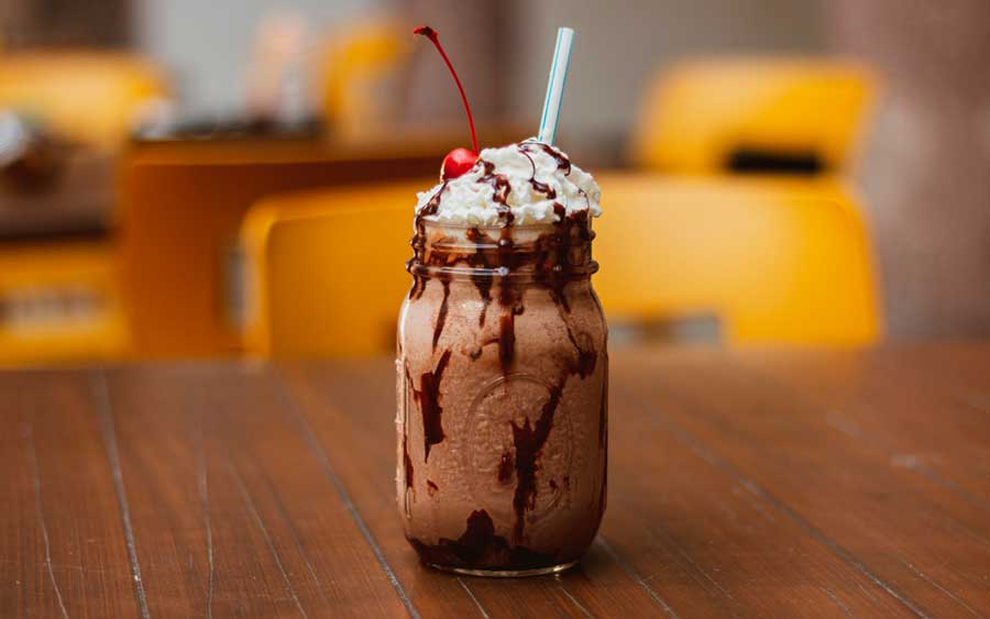 A glass of chocolate cocktail with whipped cream and cherry on top