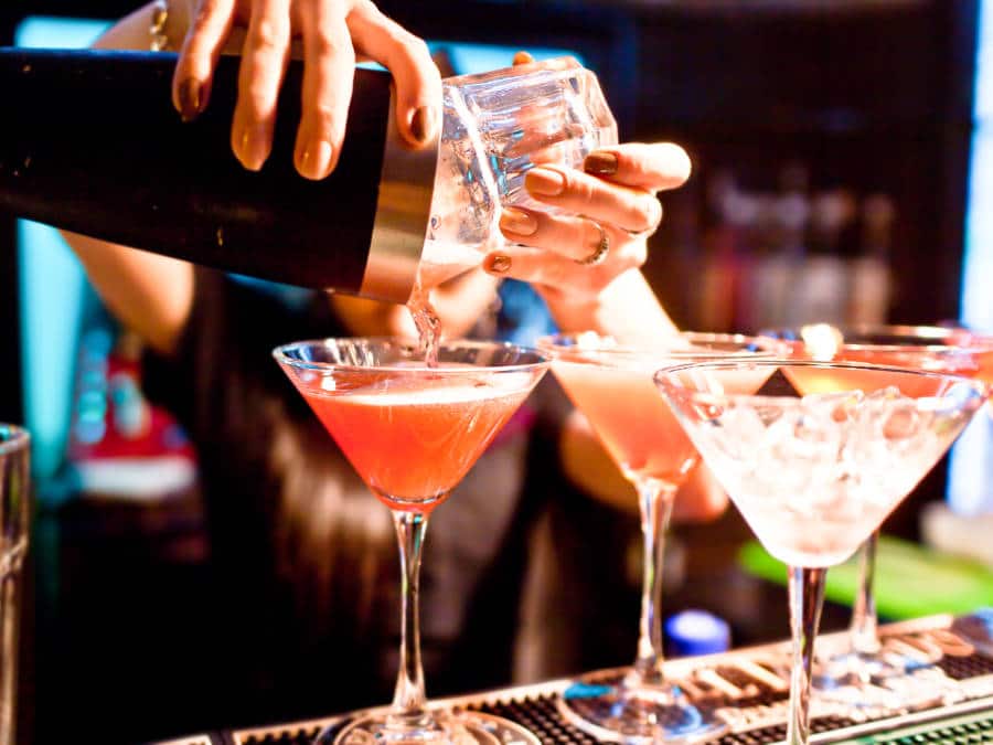 A bar tender pouring cocktails drink in the glasses