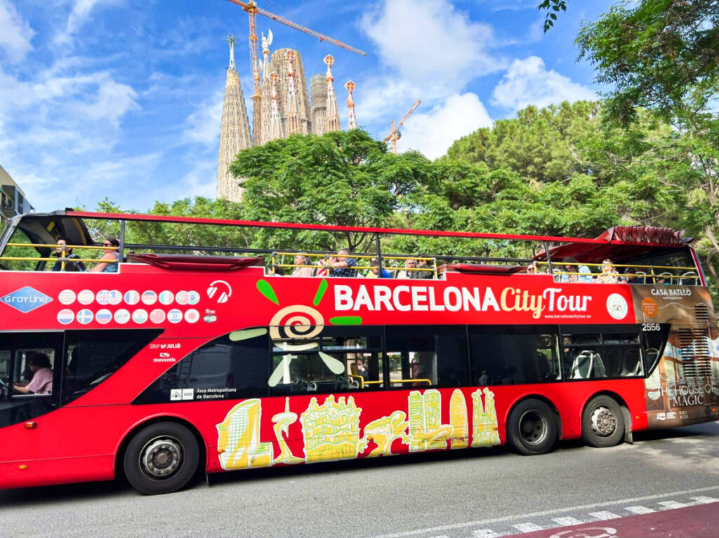 A red Barcelona City Tour bus with the Sagrada Familia in the background