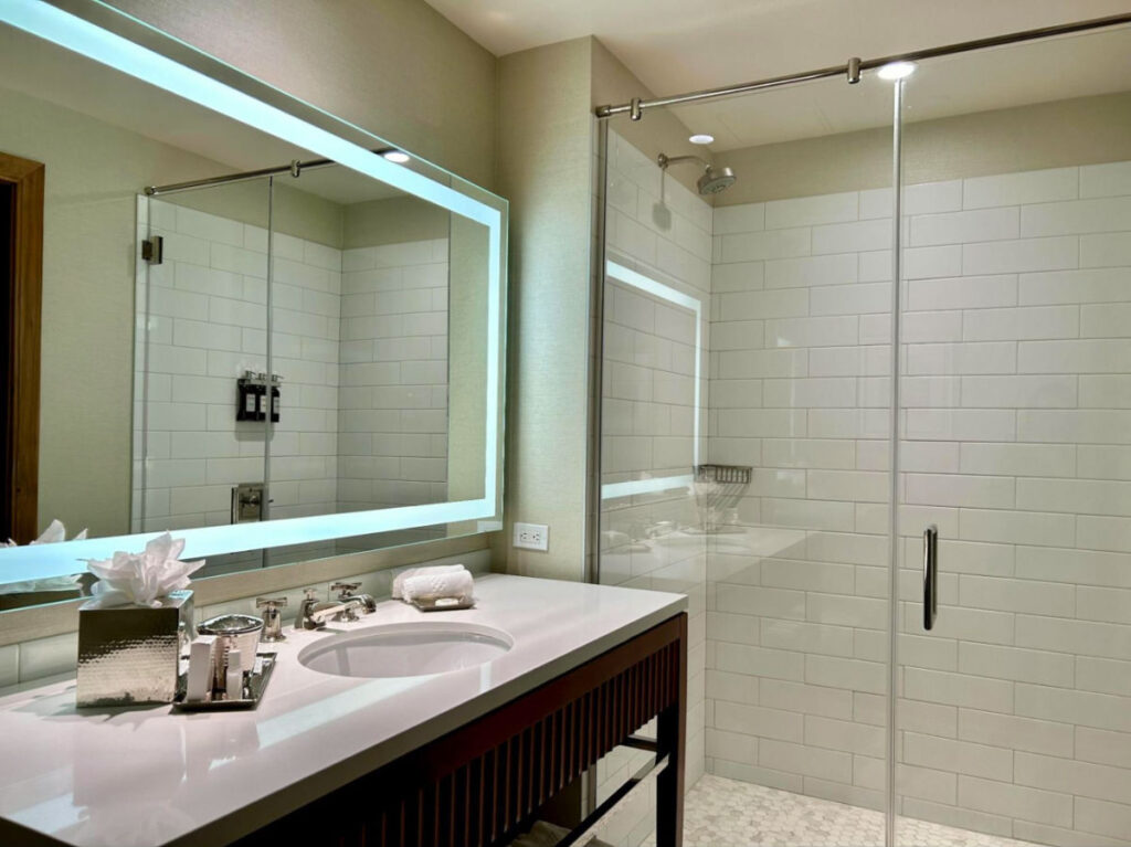 A bathroom with a glass shower door and a sink
