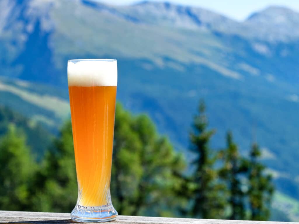 A glass of Bavarian wheat beer with the scenic mountain views in the background