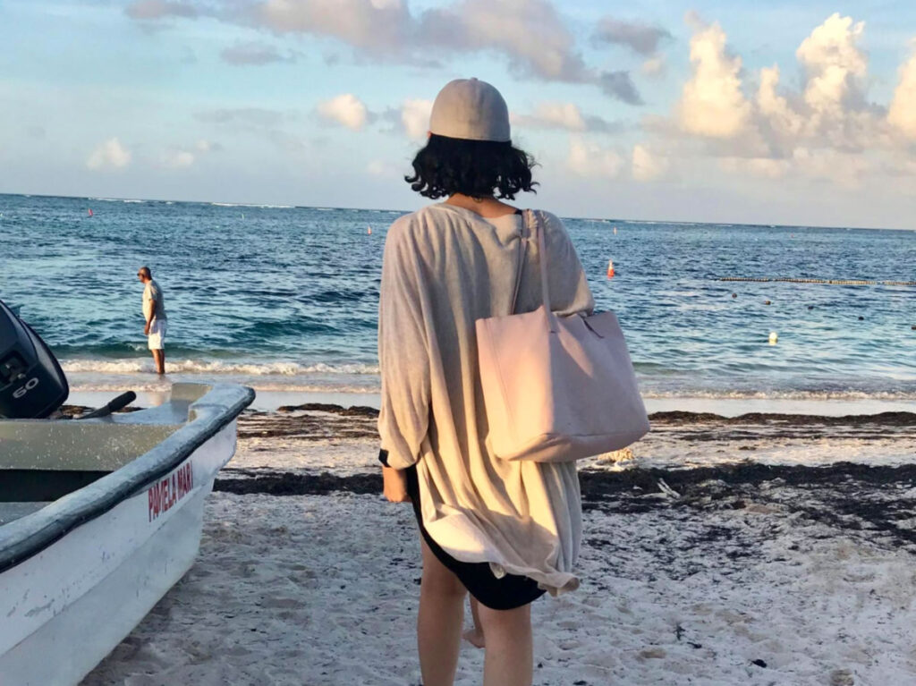 Claudicet Pena walking on Bavaro Beach, Dominican Republic, carrying a pink bag