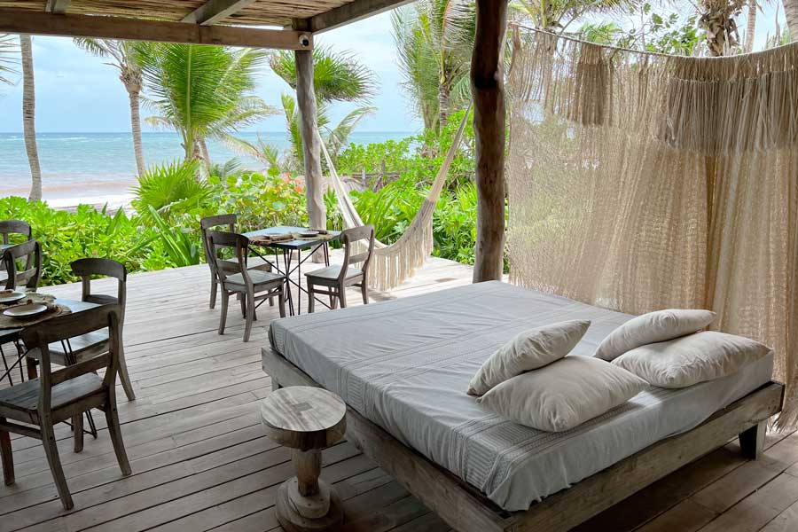 An area with bed, chairs, and tables and a beach view in La Valise Tulum