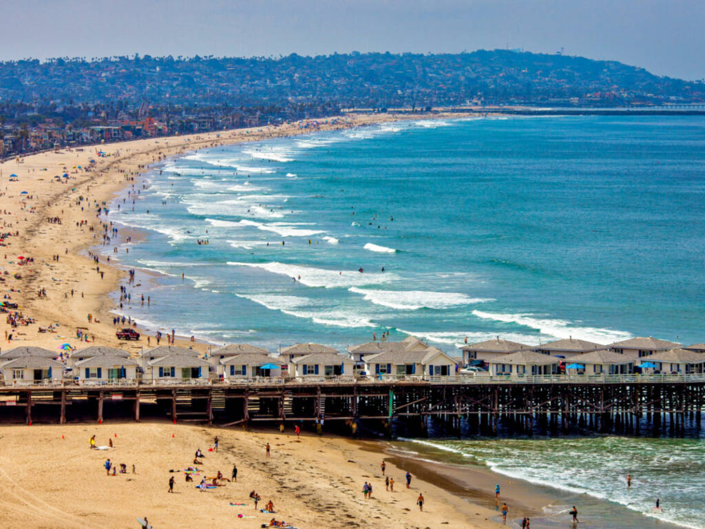 Aerial view of the Crystal Pier and the crowd at the shoreline in Pacific Beach