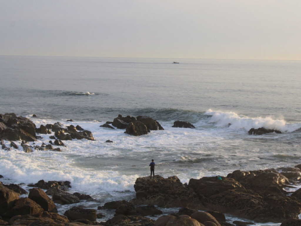 View of a man fishing at the beach near Porto
