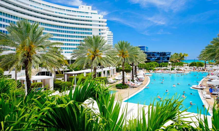View of the Beachfront Resort building and people having a swim on its pool