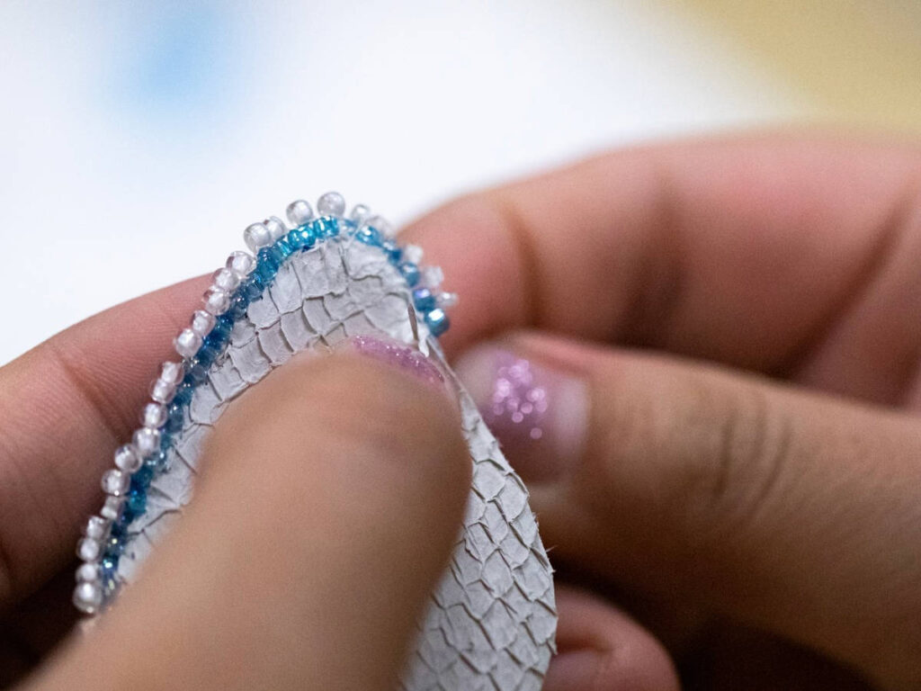 A close up look of a hand making a beadwork project