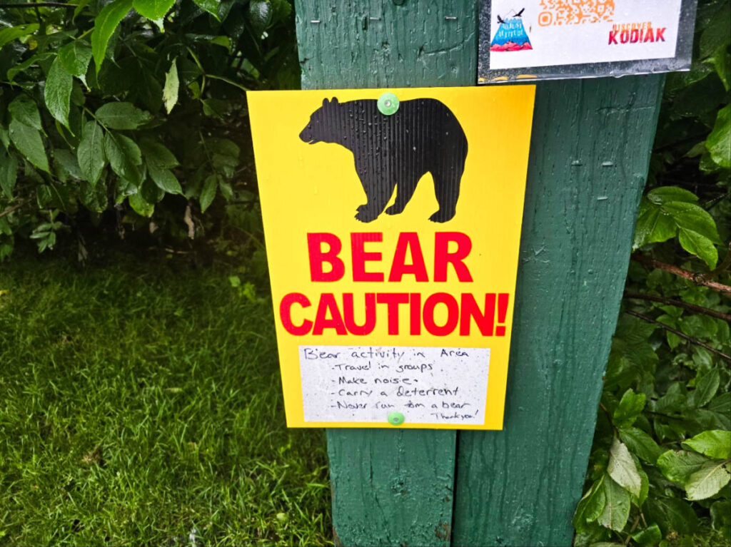 A signage of a Bear Caution on a green post