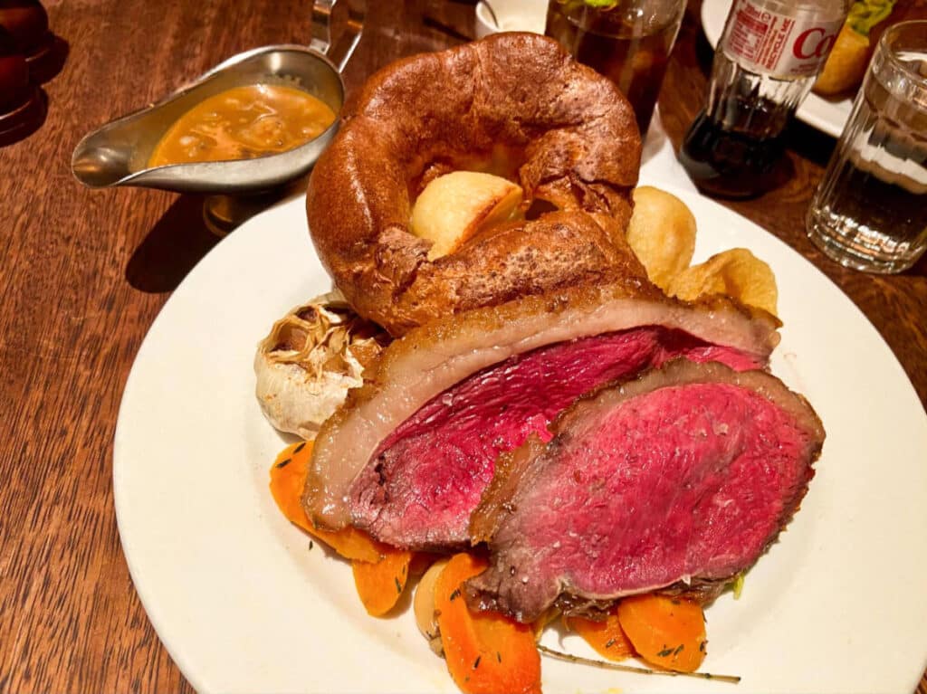 A plate with rare bed over a bed of vegetables and a giant Yorkshire Pudding from Hawksmoor