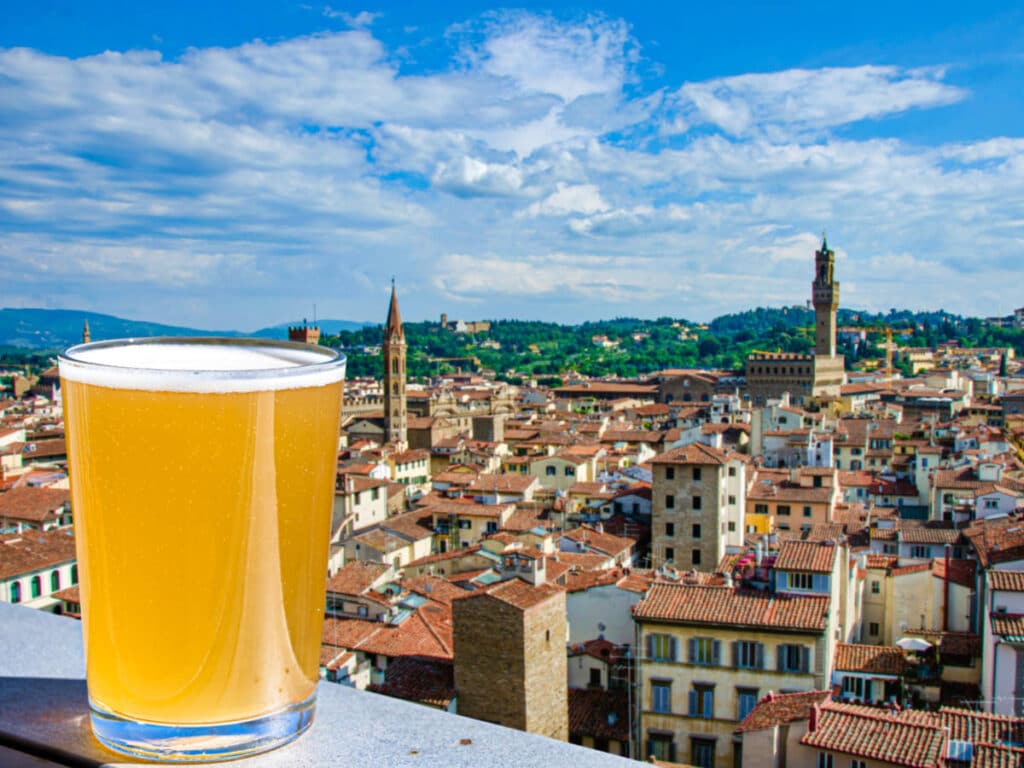 A glass of beer with the Florence historic center in the background from the rooftop bar
